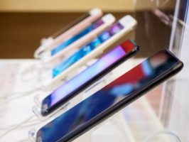 A display showcasing a variety of smartphones lined up on a stand, each with different colors and designs.