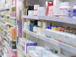 A close-up view of shelves in a pharmacy displaying various bottles and packages of medications and health products.