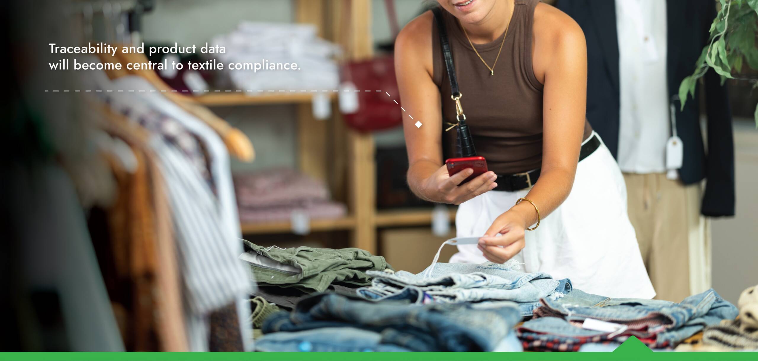Shopper scanning a garment tag on jeans with smartphone, illustrating traceability and product data for textile compliance